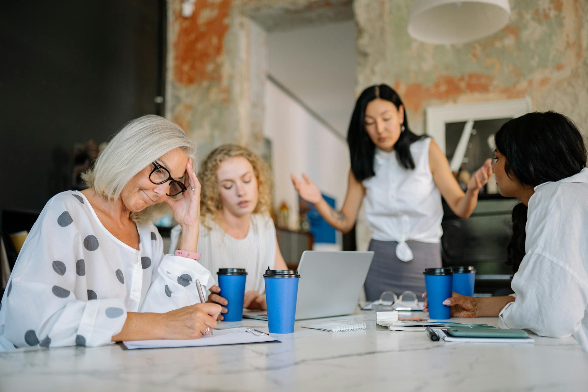 group of women having a meeting in an office and looking angry and disappointed